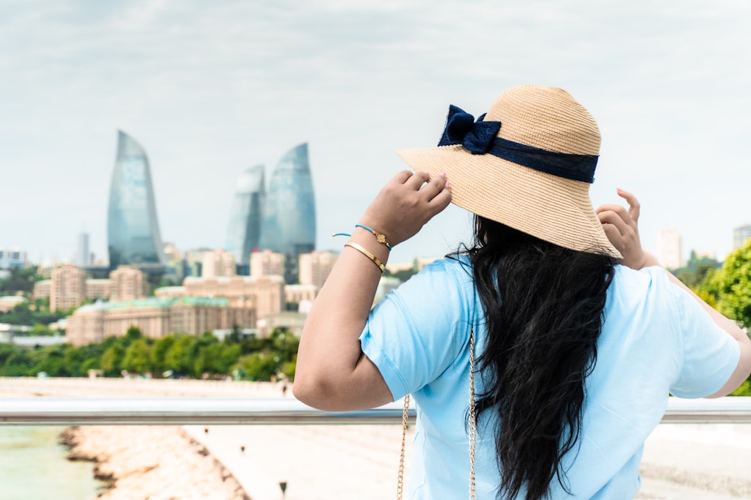 A woman wearing a wide-brimmed hat and sunscreen while walking through a sunny city, showing combined sunscreen habits