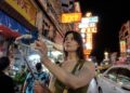 A man uses her smartphone to begin a short film practice on a busy Singapore street