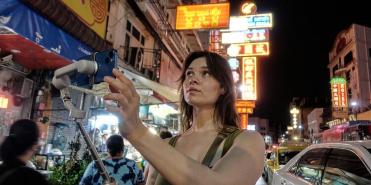 young-woman-filming-street-unsplash - SINwebzine A man uses her smartphone to begin a short film practice on a busy Singapore street