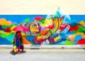 artist-painting-mural-wall-singapore-unsplash - SINwebzine A local artist painting a large Marina Bay mural on an outdoor wall near the waterfront district