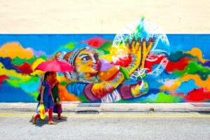 A local artist painting a large Marina Bay mural on an outdoor wall near the waterfront district