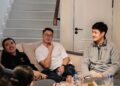 A group of Singaporean friends cheering together as they watch the Grand Prix Singapore race on a television screen at home