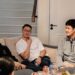 A group of Singaporean friends cheering together as they watch the Grand Prix Singapore race on a television screen at home