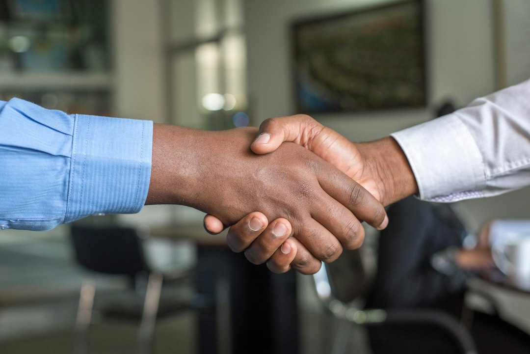 Two government representatives shake hands after signing a bilateral agreement that strengthens their country's carbon credit