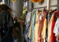 A woman carefully browsing a clothing rack at one of Singapore's secondhand platforms, looking for preloved fashion finds.