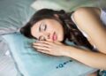 A woman achieving a sleep reset in a cool, fan-ventilated Singapore bedroom on a hot September night