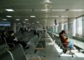 Year-end flights from Singapore when to book photo 1 - SINwebzine Traveler comparing year-end flights deals on a phone at Changi Airport