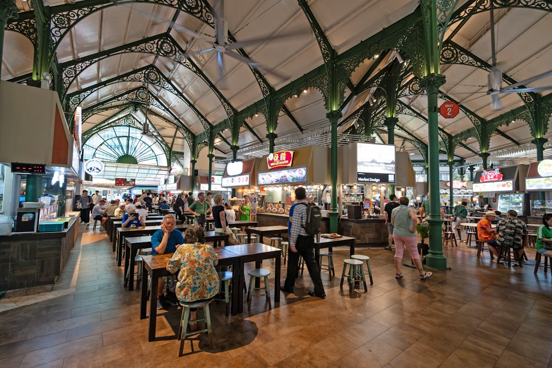 Un viaggiatore sorridente si gode un pasto economico in un affollato centro hawker di Singapore