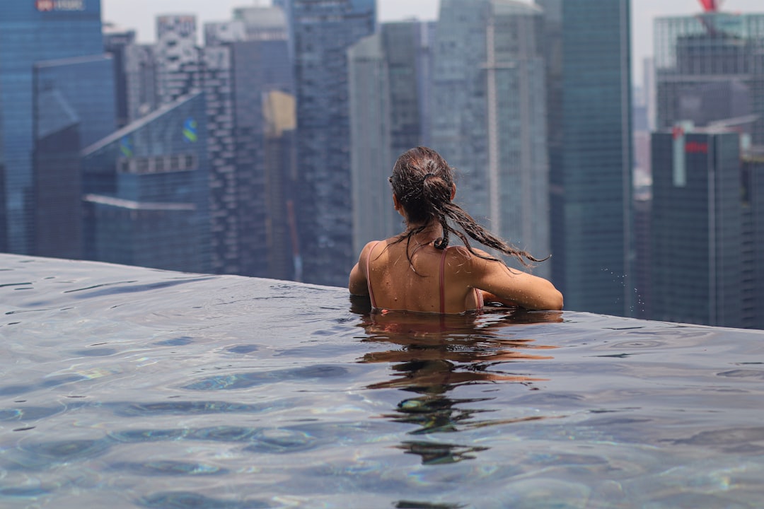 Una donna che si rilassa vicino a una piscina a sfioro durante un soggiorno di lusso a Singapore con lo skyline della città sullo sfondo