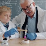 Un niño realizando talleres de ciencia prácticos en una mesa de aula, usando gafas de seguridad y mezclando líquidos coloridos.