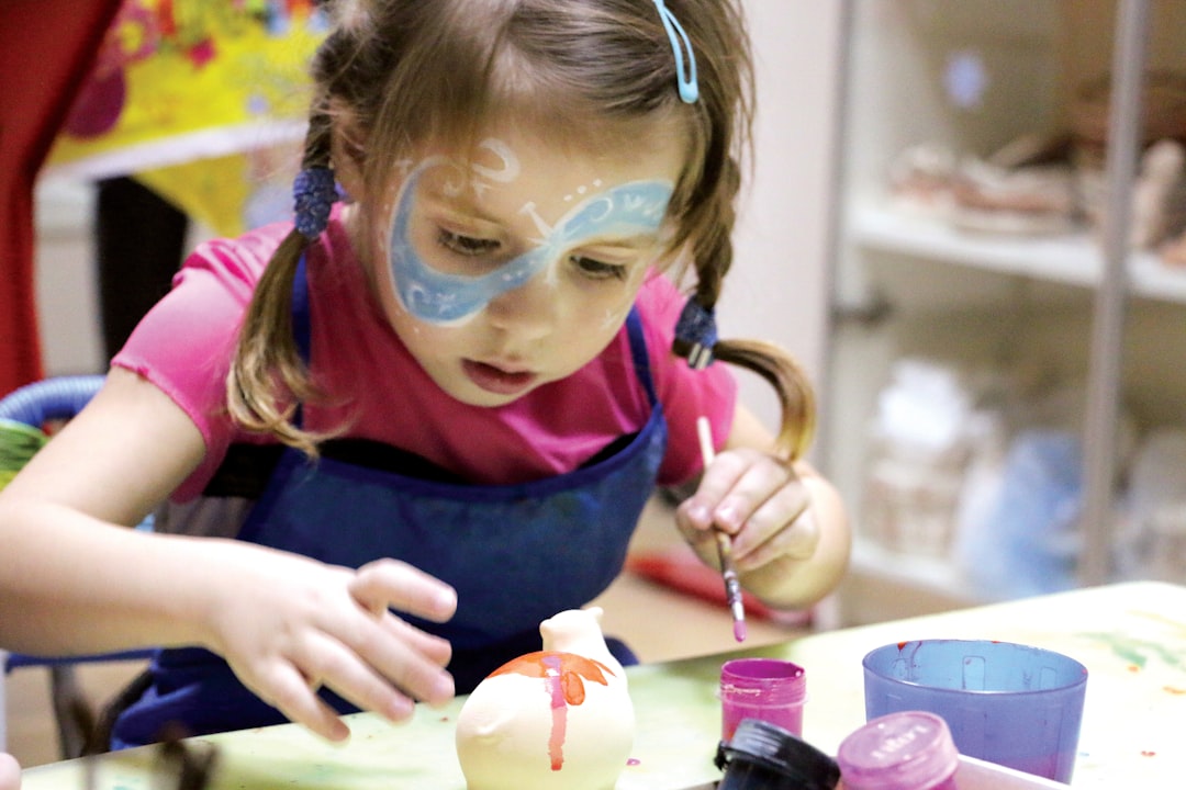 A child enjoying National Day activities at an arts and craft workshop in Singapore, painting red and white designs