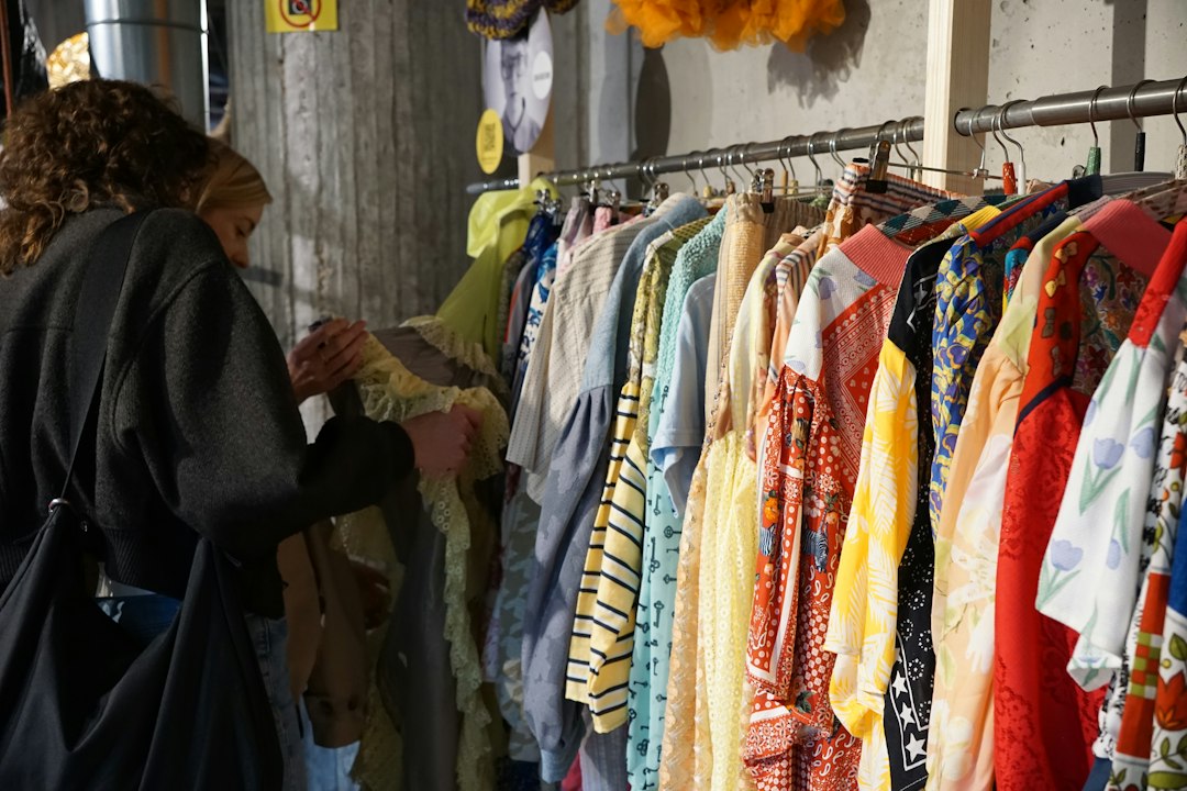 A woman carefully browsing a clothing rack at one of Singapore's secondhand platforms, looking for preloved fashion finds.